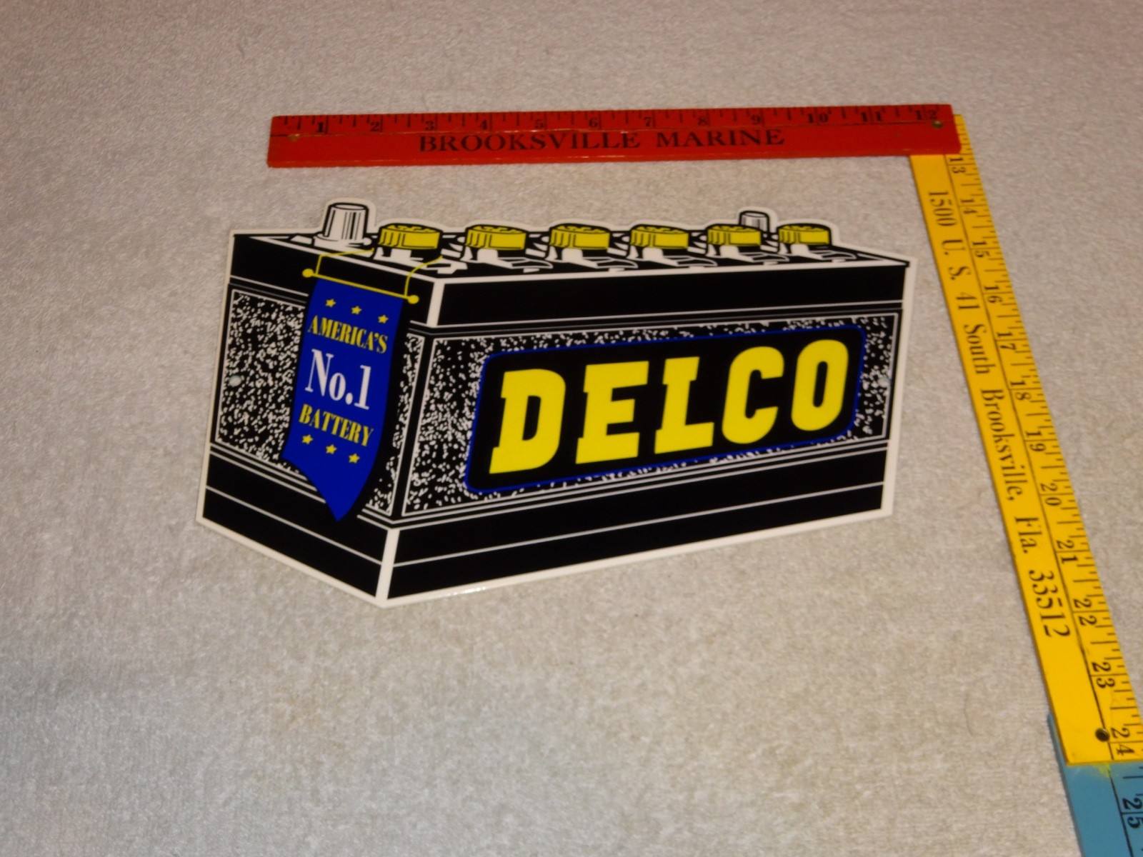 VINTAGE DELCO DIE-CUT BATTERY+ GENERAL MOTORS 12″ ENAMEL METAL GASOLINE OIL SIGN