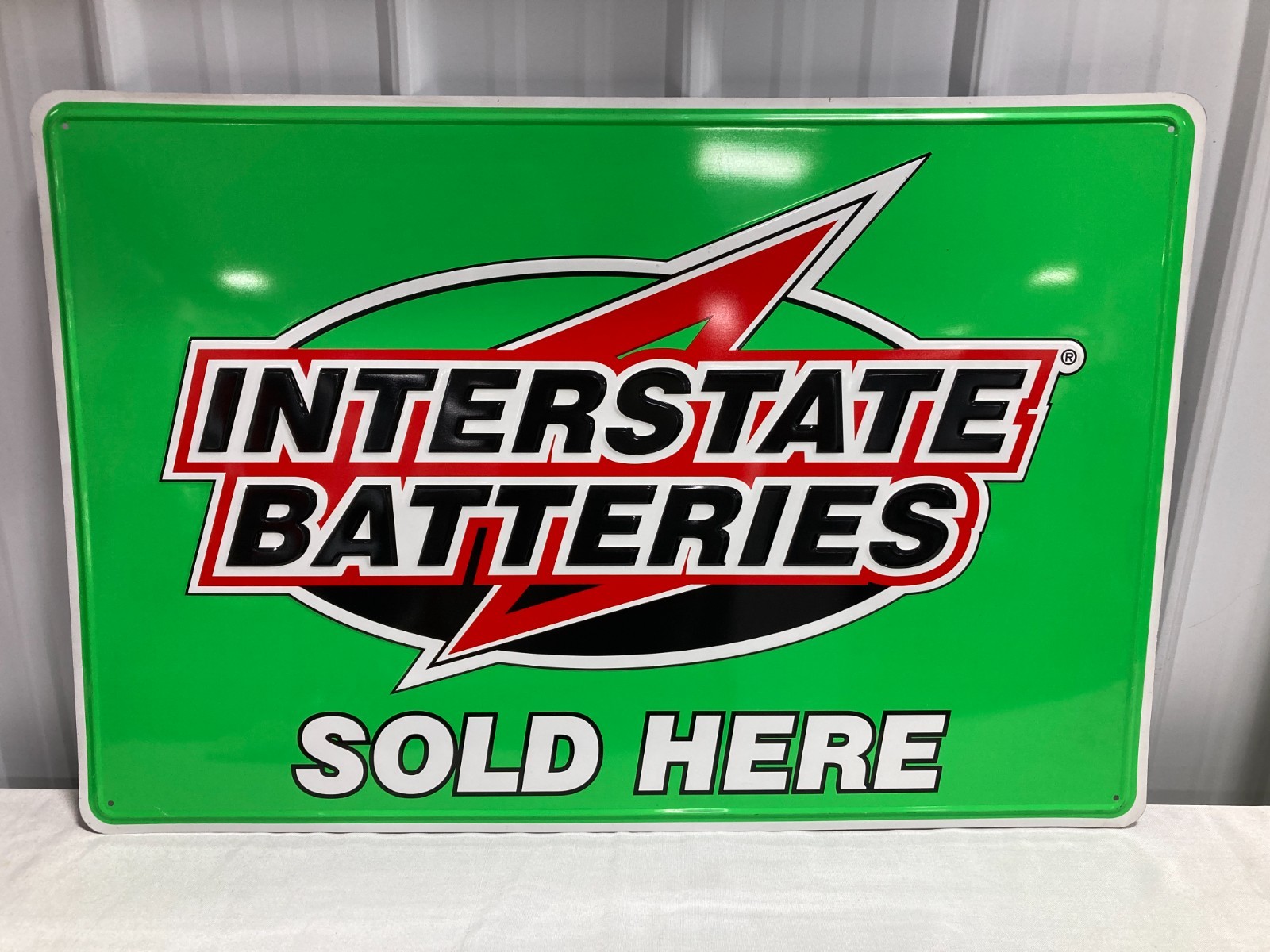 “INTERSTATE BATTERIES SOLD HERE” Embossed Metal Advertising Sign 36″ x 24″