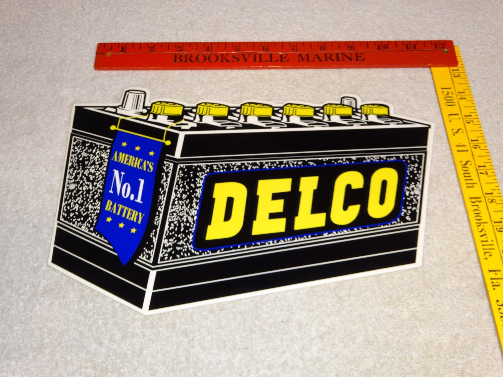 VINTAGE DELCO DIE-CUT BATTERY+ GENERAL MOTORS 12″ ENAMEL METAL GASOLINE OIL SIGN